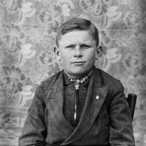 Chłopiec w wieku około 10 lat, ubrany w strój codzienny, z apaszką zawiązaną wokół szyi w charakterystyczny sposób. Oleszka (niem. Oleschka), około 1930 r.