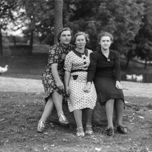 Trzy kobiety siedzące przy stawie w centrum Oleszki w czasie wolnym od obowiązków. Od lewej: Marta Lepich, Luiza Lipok nazywana też Lojską i Alicja Wieczorek. Oleszka (niem. Oleschka), lata 30. XX w.