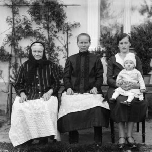 Kobiety z Oleszki (niem. Oleschka) reprezentujące cztery pokolenia rodziny. Pierwsze dwie od lewej są ubrane „po chłopsku”, tj. w tradycyjne stroje śląskie, a kobieta z dziewczynką na kolanach – „po miejsku” czy raczej „po pańsku” w prostą ciemną sukienkę, uszytą według aktualnej wówczas mody mieszczańskiej. Oleszka (niem. Oleschka), lata 30. XX w.