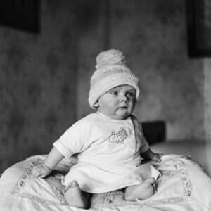 Roczne dziecko siedzące na poduszce w pokoju. Oleszka (niem. Oleschka), około 1930 r.