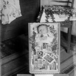 Zwłoki przedwcześnie zmarłej Jadwigi Porady w symbolicznej białej trumience. Niemowlę zostało ubrane na biało i częściowo jest przykryte obrazkami o treści religijnej, przyniesionymi zgodnie z tradycją przez chcące je pożegnać dzieci. Oleszka (niem. Oleschka), 1941 r.